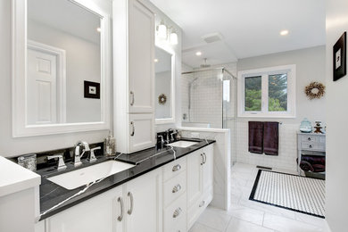 Bathroom - large traditional master white tile and porcelain tile porcelain tile and white floor bathroom idea in Ottawa with recessed-panel cabinets, white cabinets, a one-piece toilet, gray walls, an undermount sink, quartz countertops, a hinged shower door and black countertops