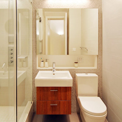 Example of a small minimalist 3/4 beige tile, white tile and ceramic tile ceramic tile and beige floor bathroom design in New York with an integrated sink, medium tone wood cabinets, a two-piece toilet, flat-panel cabinets, beige walls and solid surface countertops
