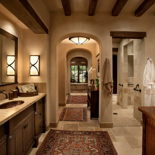 Ispirazione per una stanza da bagno padronale mediterranea di medie dimensioni con ante con bugna sagomata, ante in legno bruno, top in pietra calcarea, piastrelle beige, doccia alcova, lavabo sottopiano, pareti beige, pavimento in pietra calcarea, vasca sottopiano, WC monopezzo e piastrelle di pietra calcarea