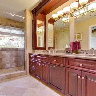 Mittelgroßes Mediterranes Badezimmer En Suite mit profilierten Schrankfronten, roten Schränken, Duschnische, Wandtoilette mit Spülkasten, beigefarbenen Fliesen, Terrakottafliesen, Unterbauwaschbecken, Granit-Waschbecken/Waschtisch, beiger Wandfarbe, Kalkstein und Falttür-Duschabtrennung in Los Angeles