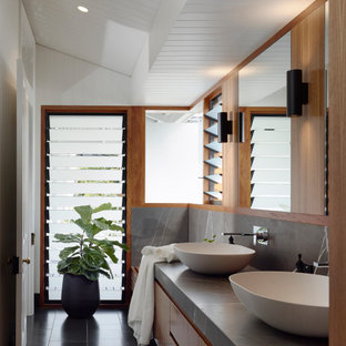 Modern inredning av ett grå grått en-suite badrum, med släta luckor, skåp i mellenmörkt trä, vita väggar, ett fristående handfat och svart golv