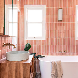 Idéer för att renovera ett mellanstort nordiskt brun brunt en-suite badrum, med ett fristående badkar, en öppen dusch, en toalettstol med separat cisternkåpa, rosa kakel, keramikplattor, rosa väggar, terrazzogolv, ett väggmonterat handfat, flerfärgat golv, med dusch som är öppen, skåp i mellenmörkt trä och träbänkskiva