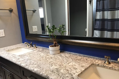 Example of a large trendy master bathroom design in Phoenix with recessed-panel cabinets, dark wood cabinets, blue walls, a drop-in sink and granite countertops