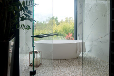 Cette image montre une grande salle de bain principale design avec des portes de placard noires, une baignoire posée, un carrelage noir et blanc, du carrelage en marbre, un plan de toilette blanc et meuble-lavabo sur pied.
