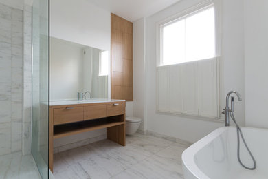 Kleines Modernes Badezimmer En Suite mit flächenbündigen Schrankfronten, hellbraunen Holzschränken, Wandtoilette, weißen Fliesen, Mineralwerkstoff-Waschtisch und weißer Waschtischplatte in London