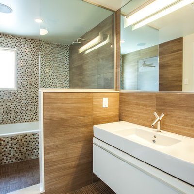 Bathroom - contemporary brown tile and wood-look tile bathroom idea in New York with an integrated sink, flat-panel cabinets, white cabinets, solid surface countertops and a one-piece toilet