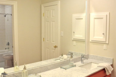 ダラスにあるお手頃価格の中くらいなトラディショナルスタイルのおしゃれな子供用バスルーム (落し込みパネル扉のキャビネット、赤いキャビネット、大理石の洗面台、白いタイル、セラミックタイル、アルコーブ型浴槽、シャワー付き浴槽	、アンダーカウンター洗面器、グレーの壁、セラミックタイルの床) の写真