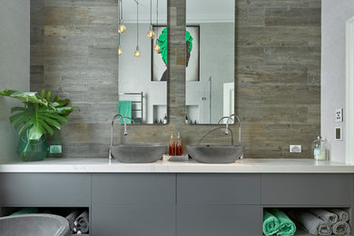 Foto de cuarto de baño principal contemporáneo con puertas de armario grises, lavabo sobreencimera, suelo marrón, armarios con paneles lisos, baldosas y/o azulejos marrones y paredes grises