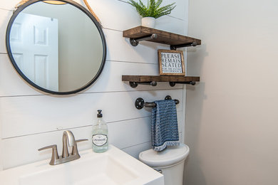 Foto de cuarto de baño campestre pequeño con puertas de armario de madera en tonos medios, sanitario de dos piezas, paredes grises, suelo vinílico, lavabo integrado, encimera de madera y encimeras blancas