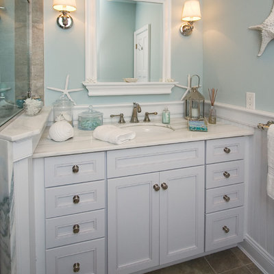 Example of a beach style beige tile bathroom design in New York with an undermount sink, recessed-panel cabinets and white cabinets
