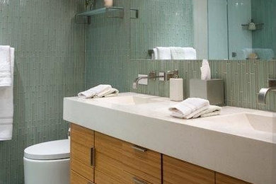 Example of a mid-sized minimalist master green tile and glass tile alcove shower design in New York with an integrated sink, flat-panel cabinets, light wood cabinets and a one-piece toilet