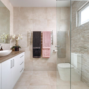 Design ideas for a mid-sized contemporary 3/4 bathroom in Adelaide with flat-panel cabinets, white cabinets, a corner shower, a one-piece toilet, beige tile, beige walls, a vessel sink, wood benchtops, beige floor and brown benchtops.