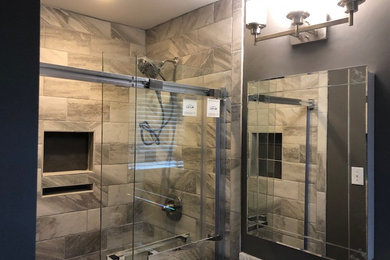 Small transitional 3/4 gray tile and ceramic tile bathroom photo in Charlotte with recessed-panel cabinets, black cabinets, a two-piece toilet, gray walls, an undermount sink, solid surface countertops and white countertops