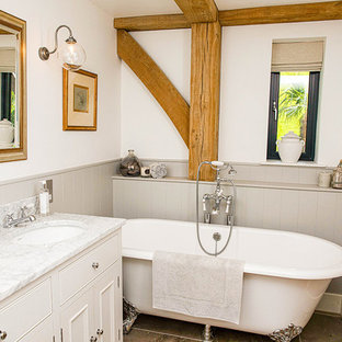 Inspiration for a farmhouse ensuite bathroom in Wiltshire with recessed-panel cabinets, white cabinets, a claw-foot bath, white walls, a submerged sink and white worktops.