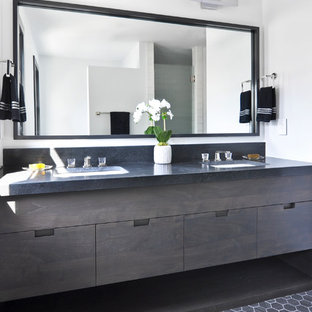 Kleines Modernes Badezimmer En Suite mit flächenbündigen Schrankfronten, braunen Schränken, Eckdusche, Wandtoilette mit Spülkasten, weißen Fliesen, Terrakottafliesen, weißer Wandfarbe, Kalkstein, Unterbauwaschbecken, Granit-Waschbecken/Waschtisch, schwarzem Boden, Falttür-Duschabtrennung und schwarzer Waschtischplatte in Nashville