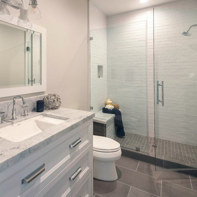 Corner shower - mid-sized country kids' gray tile and ceramic tile ceramic tile and gray floor corner shower idea in San Francisco with shaker cabinets, white cabinets, a two-piece toilet, gray walls, an undermount sink, marble countertops, a hinged shower door and gray countertops
