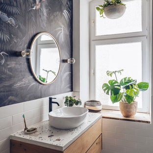 Modernes Badezimmer mit flächenbündigen Schrankfronten, hellbraunen Holzschränken, weißen Fliesen, Metrofliesen, schwarzer Wandfarbe, Aufsatzwaschbecken, grauem Boden und weißer Waschtischplatte in Berlin