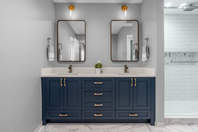 This is an example of a medium sized traditional ensuite bathroom in Vancouver with shaker cabinets, blue cabinets, a double shower, a one-piece toilet, white tiles, metro tiles, grey walls, porcelain flooring, a submerged sink, engineered stone worktops, grey floors, a sliding door and white worktops.