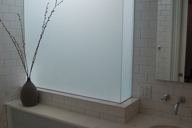 Inredning av ett modernt litet badrum för barn, med ett undermonterad handfat, släta luckor, grå skåp, marmorbänkskiva, ett badkar i en alkov, en dusch/badkar-kombination, vit kakel, tunnelbanekakel, vita väggar och marmorgolv