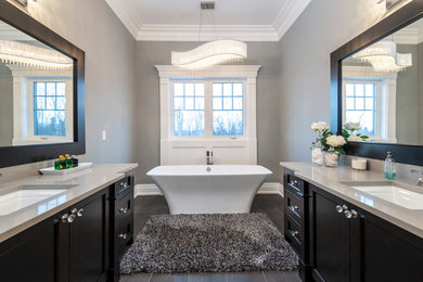 Foto på ett stort vintage en-suite badrum, med ett fristående badkar, bänkskiva i kvarts, grå väggar och ett undermonterad handfat