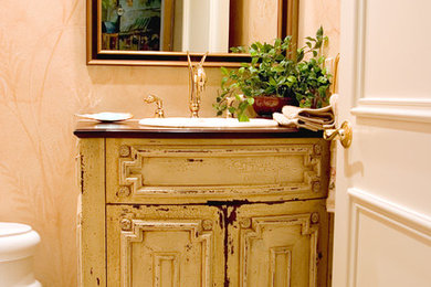 Ejemplo de cuarto de baño tradicional con armarios tipo mueble, puertas de armario con efecto envejecido y encimera de madera