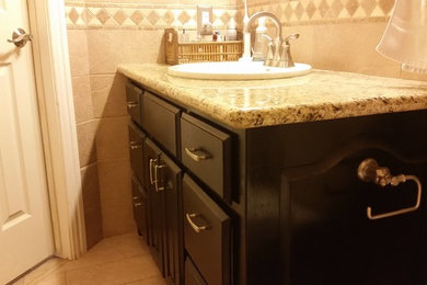 Example of a mid-sized classic kids' beige tile and porcelain tile porcelain tile doorless shower design in Austin with a drop-in sink, raised-panel cabinets, black cabinets, granite countertops, a two-piece toilet and orange walls