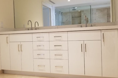マイアミにある高級な小さなコンテンポラリースタイルのおしゃれな浴室 (フラットパネル扉のキャビネット、白いキャビネット、御影石の洗面台、白い洗面カウンター) の写真