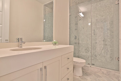 Photo of a medium sized traditional shower room bathroom in Toronto with shaker cabinets, white cabinets, an alcove shower, a two-piece toilet, grey tiles, white tiles, stone tiles, grey walls, marble flooring, a submerged sink, quartz worktops, grey floors and a hinged door.