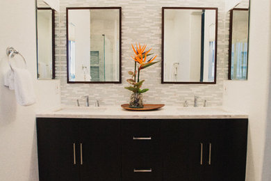 ニューオリンズにあるコンテンポラリースタイルのおしゃれな浴室 (フラットパネル扉のキャビネット、黒いキャビネット、グレーのタイル、白いタイル、ボーダータイル、白い壁、磁器タイルの床、珪岩の洗面台、ベージュの床) の写真