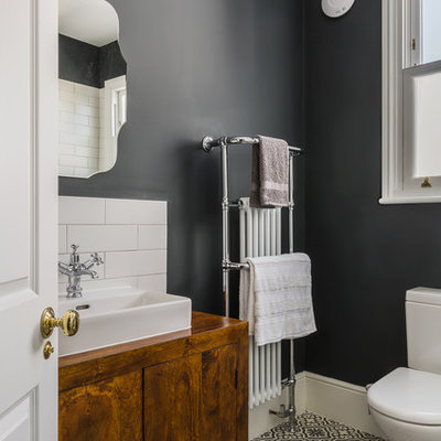 Inspiration for a small timeless ceramic tile bathroom remodel in London with flat-panel cabinets, dark wood cabinets, a one-piece toilet, gray walls and a vessel sink