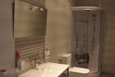 Modelo de cuarto de baño actual de tamaño medio con ducha esquinera, sanitario de dos piezas, aseo y ducha y lavabo suspendido
