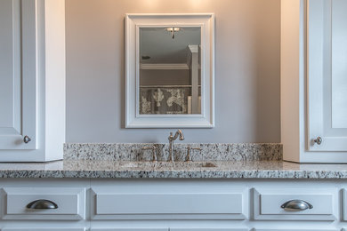 Foto de cuarto de baño tradicional pequeño con armarios con paneles con relieve, puertas de armario blancas, paredes beige, aseo y ducha, lavabo bajoencimera y encimera de granito