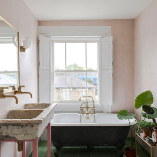 Design ideas for an eclectic bathroom in London with a claw-foot bath, pink walls, a console sink, green floors and double sinks.