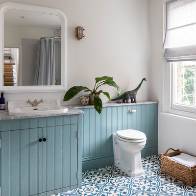 Elegant kids' mosaic tile floor and blue floor bathroom photo in London with beaded inset cabinets, granite countertops, blue cabinets, a one-piece toilet, white walls, a drop-in sink and gray countertops