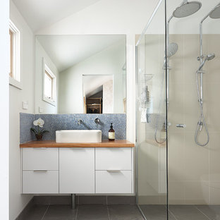 Immagine di una piccola stanza da bagno padronale contemporanea con lavabo a bacinella, ante bianche, top in legno, doccia doppia, piastrelle blu, pareti bianche, WC monopezzo, piastrelle in ceramica, pavimento in gres porcellanato, top marrone, ante con bugna sagomata, pavimento grigio e porta doccia a battente