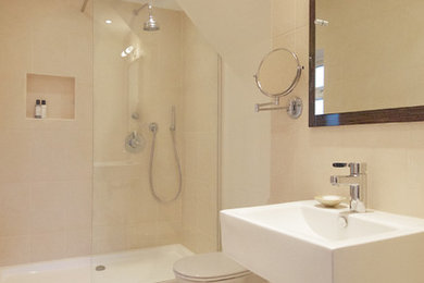 Design ideas for a contemporary ensuite bathroom in Surrey with a walk-in shower, a one-piece toilet, beige tiles, ceramic tiles, beige walls, ceramic flooring and a wall-mounted sink.