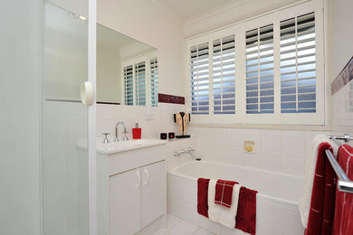 Пример оригинального дизайна: главная ванная комната среднего размера в стиле модернизм с монолитной раковиной, плоскими фасадами, белыми фасадами, накладной ванной, угловым душем, белой плиткой, керамической плиткой, белыми стенами и полом из керамической плитки