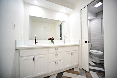 Diseño de cuarto de baño principal contemporáneo de tamaño medio con lavabo bajoencimera, armarios con paneles empotrados, puertas de armario blancas, encimera de vidrio, baldosas y/o azulejos grises, baldosas y/o azulejos de porcelana, paredes blancas y suelo de baldosas de porcelana
