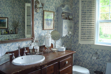 モントリオールにあるカントリー風のおしゃれな浴室 (家具調キャビネット、中間色木目調キャビネット、青い壁、オーバーカウンターシンク、木製洗面台) の写真
