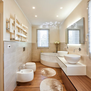 Esempio di una stanza da bagno padronale minimal con ante lisce, ante bianche, vasca ad angolo, lavabo a bacinella, bidè, piastrelle beige, pareti beige, pavimento in legno massello medio, pavimento marrone e top bianco