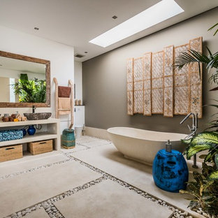 Design ideas for a tropical master bathroom in Perth with open cabinets, beige cabinets, a freestanding tub, grey walls, concrete floors, a vessel sink, grey floor and beige benchtops.