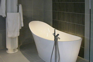 他の地域にある高級な中くらいなコンテンポラリースタイルのおしゃれなマスターバスルーム (置き型浴槽、グレーのタイル、磁器タイル、グレーの壁、磁器タイルの床) の写真