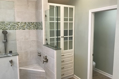 Modelo de cuarto de baño tradicional renovado de tamaño medio con armarios con paneles con relieve, puertas de armario de madera en tonos medios, ducha esquinera, baldosas y/o azulejos grises, baldosas y/o azulejos en mosaico, paredes beige, suelo laminado, aseo y ducha, lavabo bajoencimera, encimera de cuarcita, suelo marrón, ducha abierta y encimeras grises