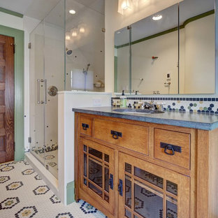 Inspiration for a mid-sized arts and crafts bathroom in New York with furniture-like cabinets, medium wood cabinets, a two-piece toilet, white tile, white walls, porcelain floors, an undermount sink, granite benchtops, multi-coloured floor, a hinged shower door and grey benchtops.