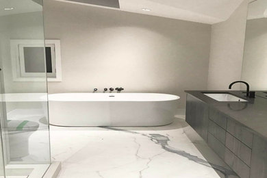 Large minimalist master gray tile and marble tile marble floor and white floor bathroom photo in Toronto with flat-panel cabinets, dark wood cabinets, a one-piece toilet, gray walls, an undermount sink, granite countertops, a hinged shower door and black countertops