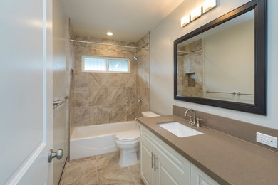 ハワイにある中くらいなトランジショナルスタイルのおしゃれなバスルーム (浴槽なし) (レイズドパネル扉のキャビネット、白いキャビネット、アルコーブ型浴槽、シャワー付き浴槽	、分離型トイレ、ベージュのタイル、セラミックタイル、ベージュの壁、セラミックタイルの床、アンダーカウンター洗面器、人工大理石カウンター、ベージュの床、シャワーカーテン) の写真