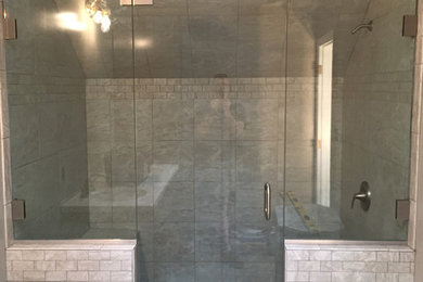 Example of a mid-sized classic brown tile and stone tile alcove shower design in Other with recessed-panel cabinets, black cabinets, brown walls, an undermount sink, solid surface countertops and a hinged shower door