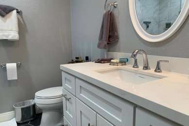 Example of a minimalist white tile black floor bathroom design in Orange County with a one-piece toilet and gray walls