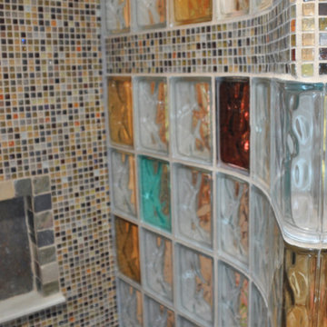 Walk in shower with colored glass blocks and a mosaic tile row