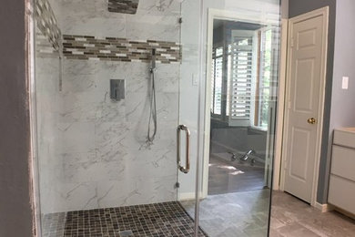 Inspiration for a large transitional master white tile and marble tile limestone floor and beige floor corner shower remodel in Houston with flat-panel cabinets, white cabinets, a one-piece toilet, gray walls, an undermount sink, limestone countertops and a hinged shower door